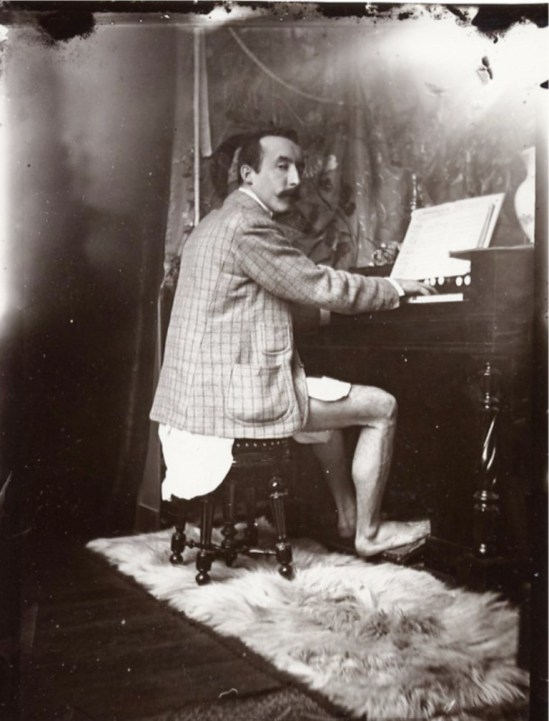 Alphonse Marie Mucha. Paul Gauguin playing Mucha’s harmonium in his studio, Rue de la Grande Chaumière, Paris 1893-1894 Via muchafoundation