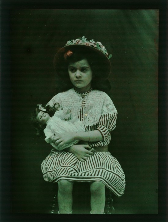 Eugène Blondelet. Fillette assise tenant une poupée 1907-1915. Autochrome. Via bnf